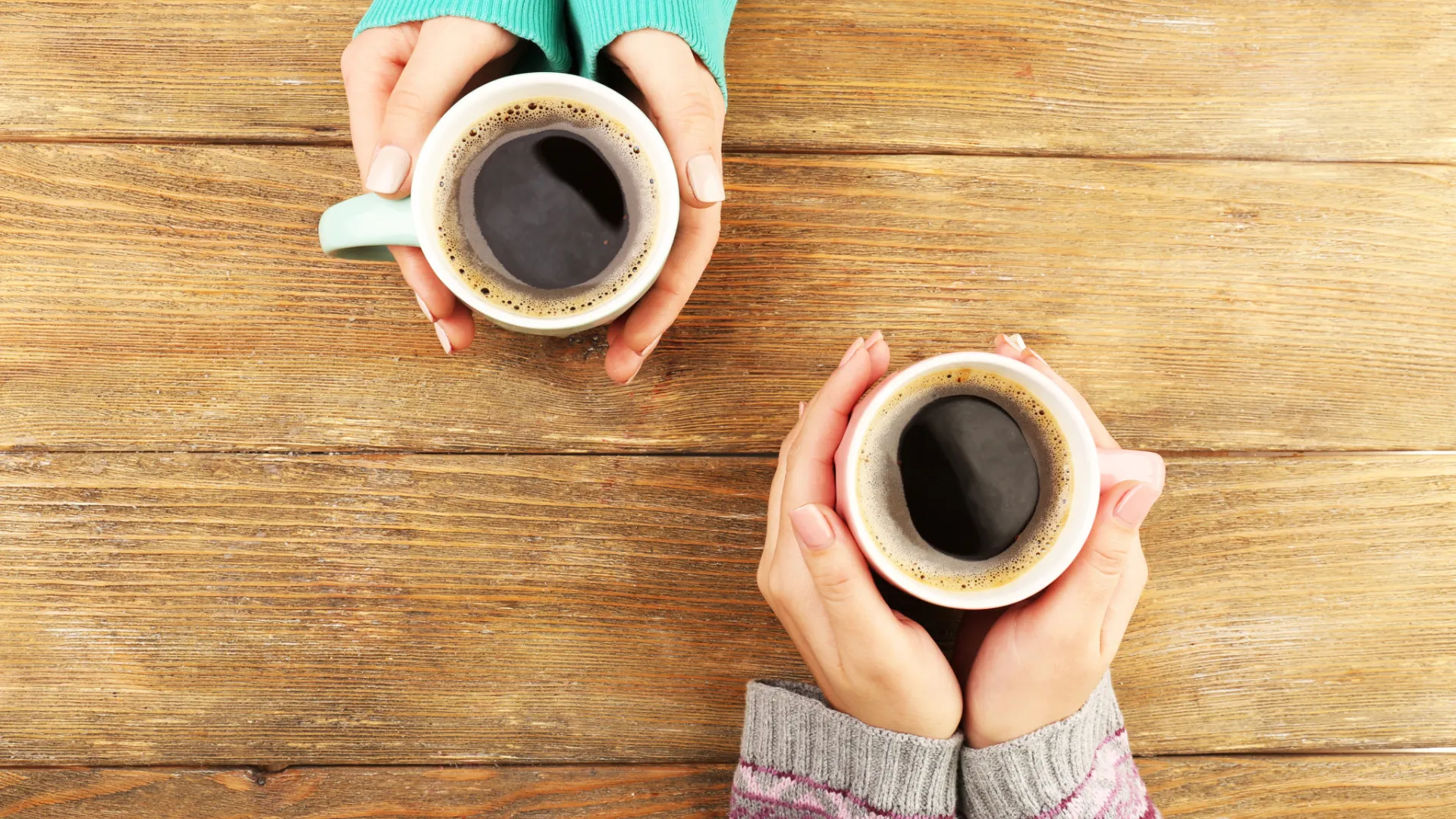 Two pairs of hands holding coffee cups