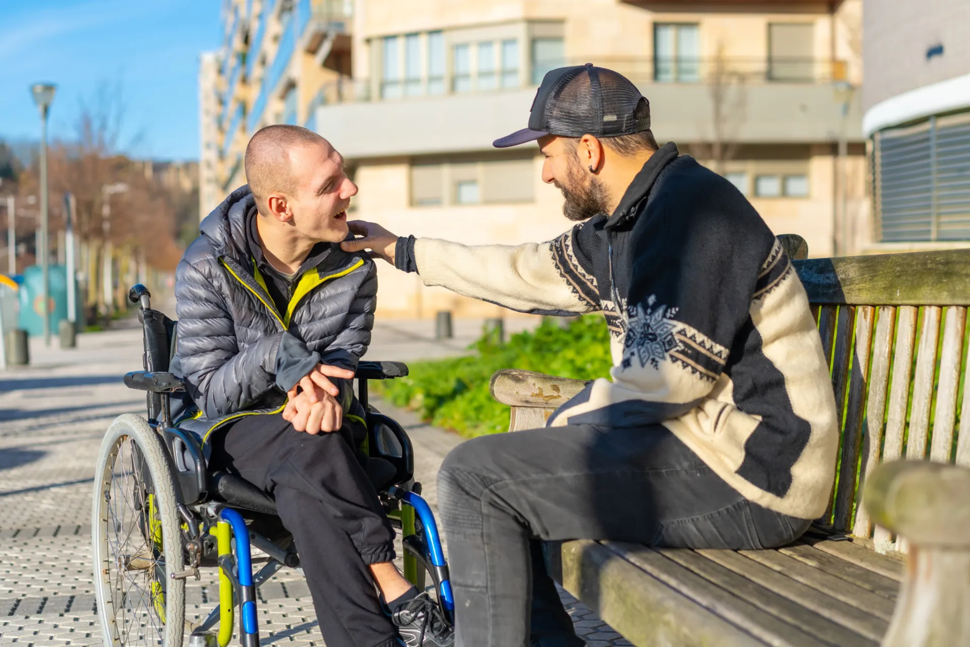 Man sitting on a bench talking to a man in a wheelchair