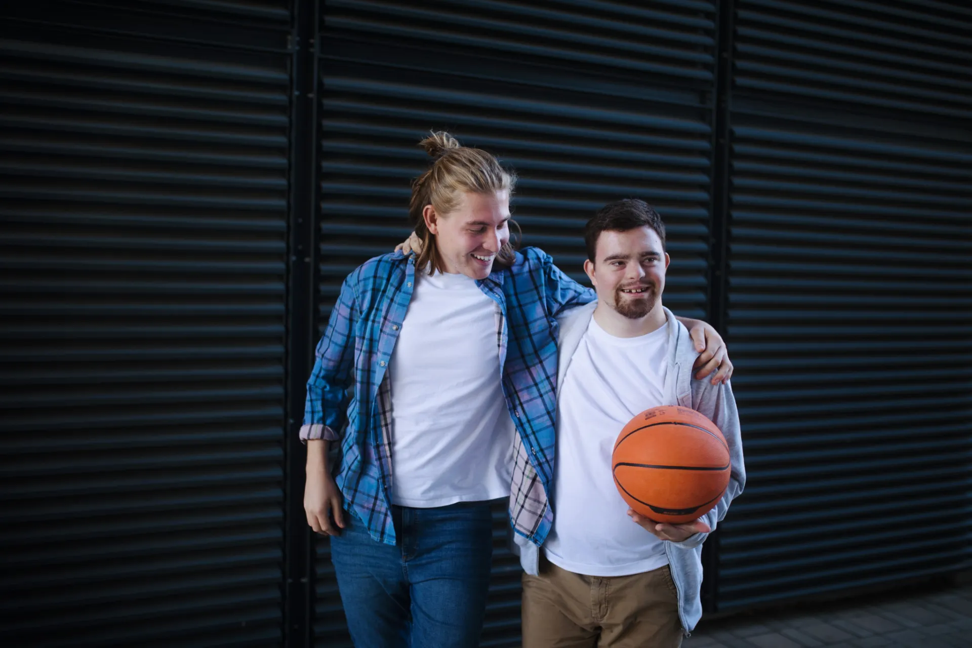Two men posing with a basketball